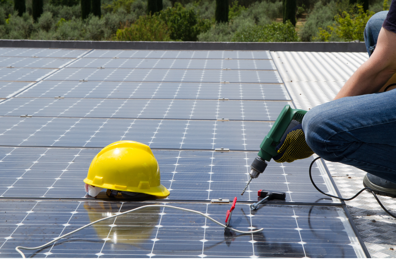 homme qui visse des panneaux solaires sur un toit