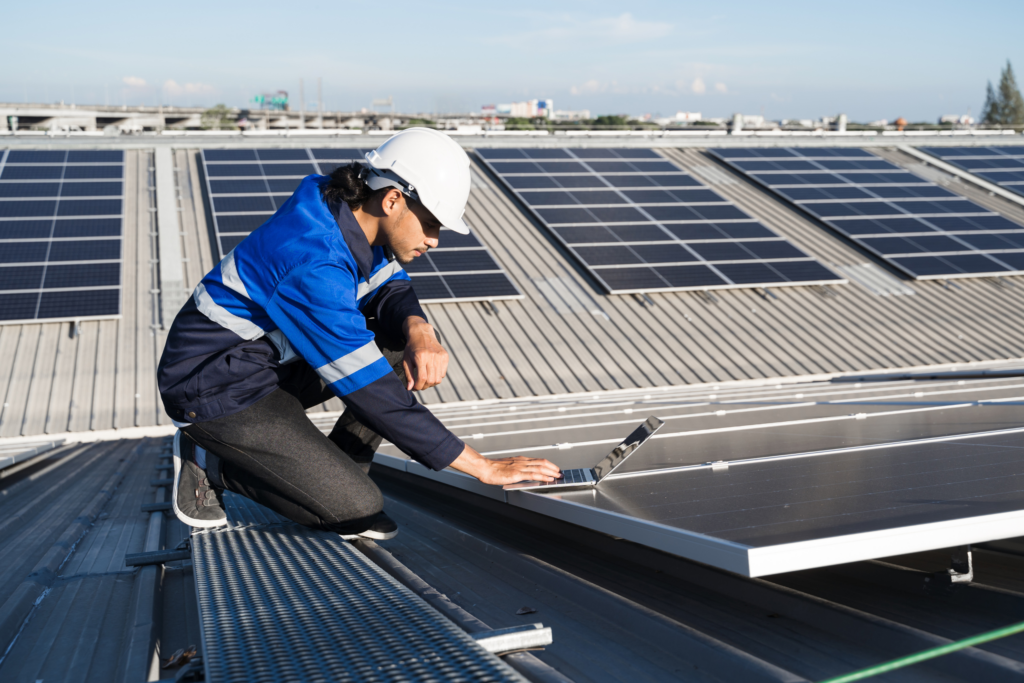 homme sur un toit qui controle des panneaux solaires
