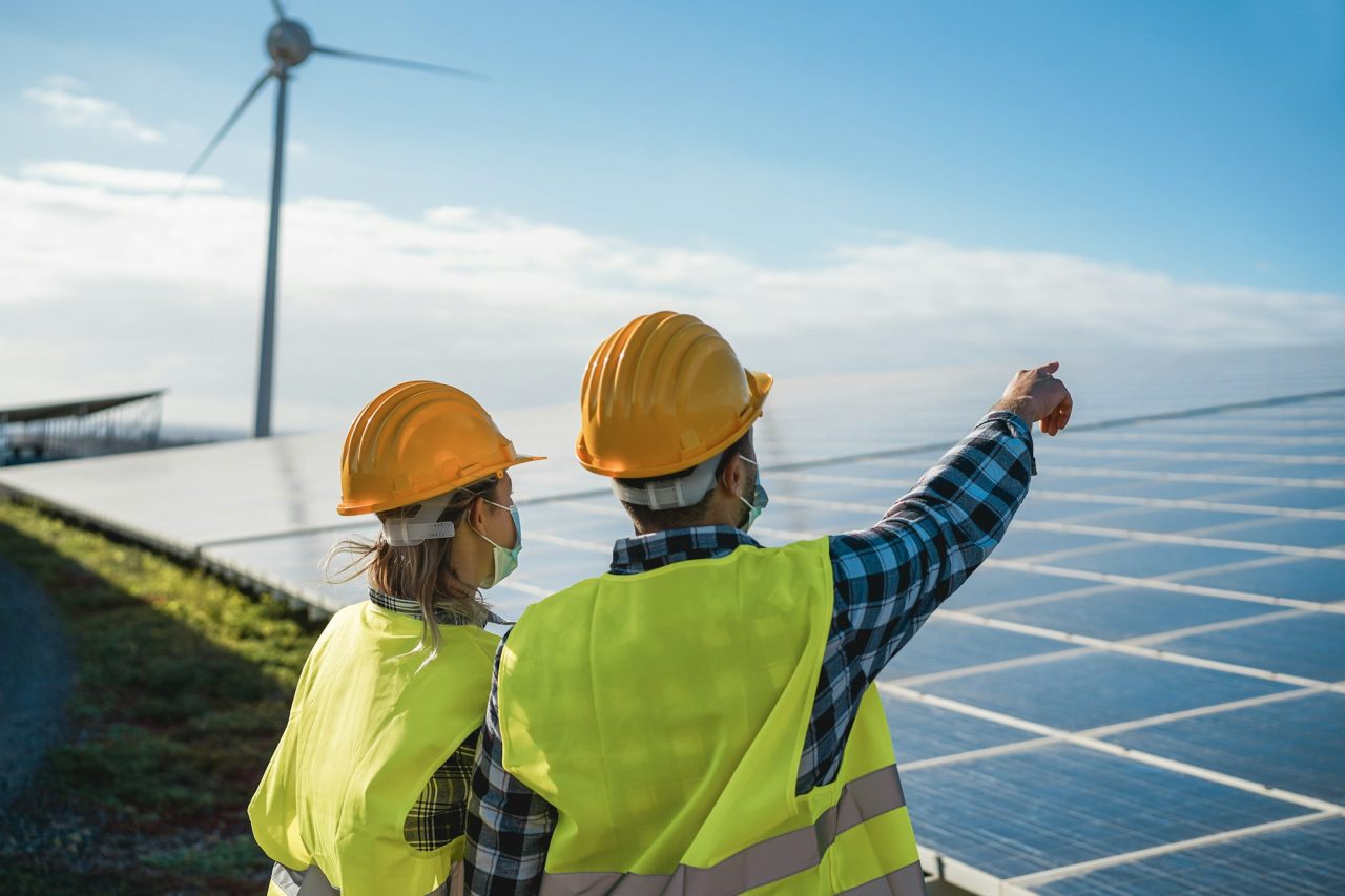 people working for solar panels and wind turbines at renewable energy farm wearing safety masks.jpg