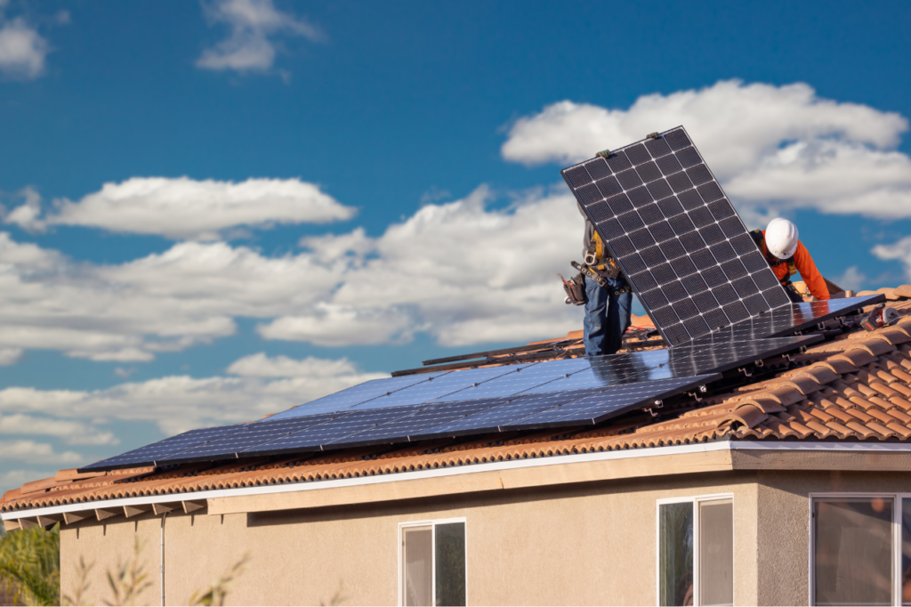 techniciens qui posent un panneau solaire sur un toit de maison