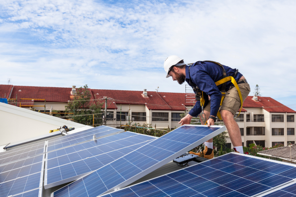 artisan sur un toit qui pose un panneau solaire